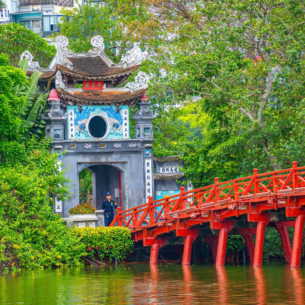Ha Noi, VIETNAM - MAY 08 2023: Red Bridge- The Huc Bridge in Hoan Kiem Lake, his is a lake in the historical center of Hanoi, the capital city of Vietnam, The beauty Phoenix-flower on Hoan Kiem lake